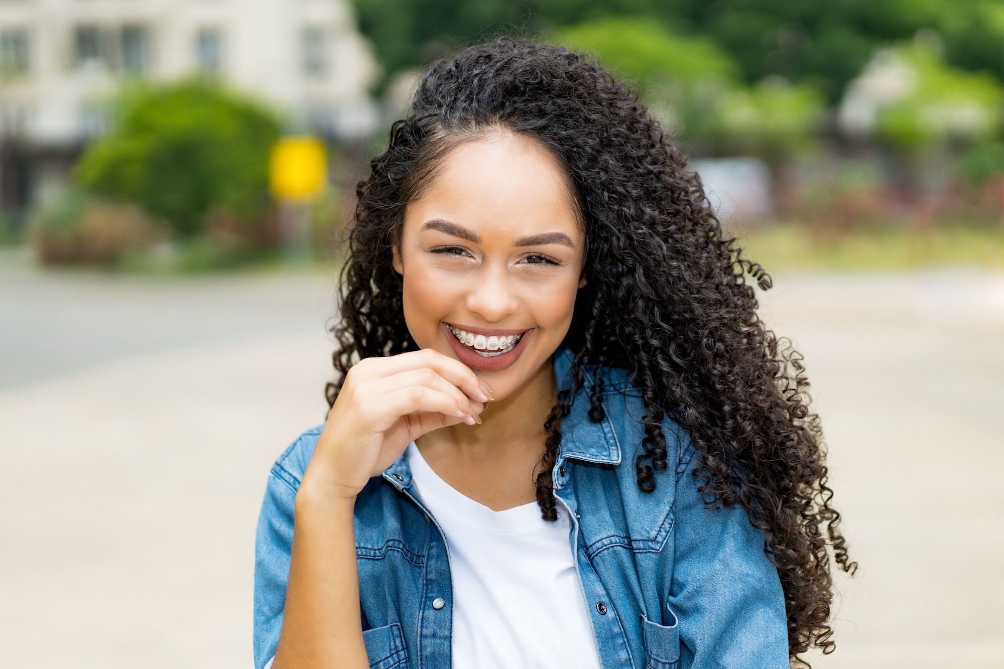 Pretty brazilian young adult woman with retainer outdoor in summer in city